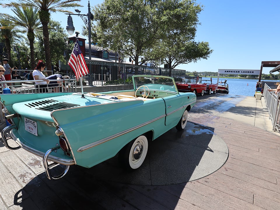 a teal amphicar at disney springs in front of the water