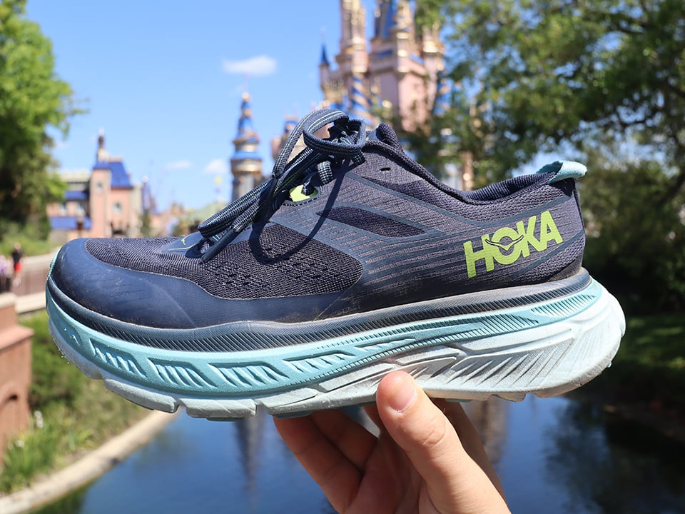 a pair of blue hoka shoes in front of disney castle