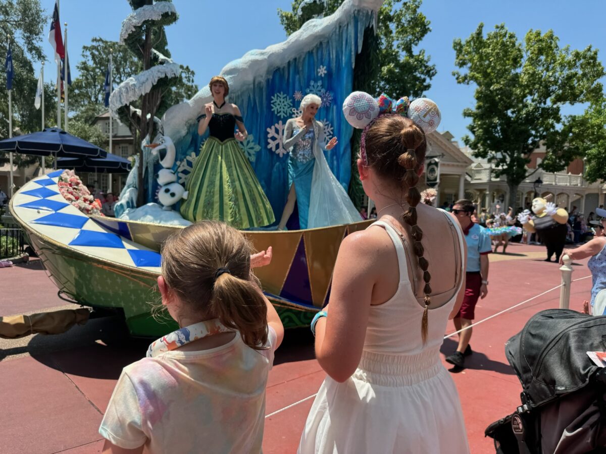 Anna & Elsa wave to fans in the crowd. (© John Gullion/Hey Orlando).